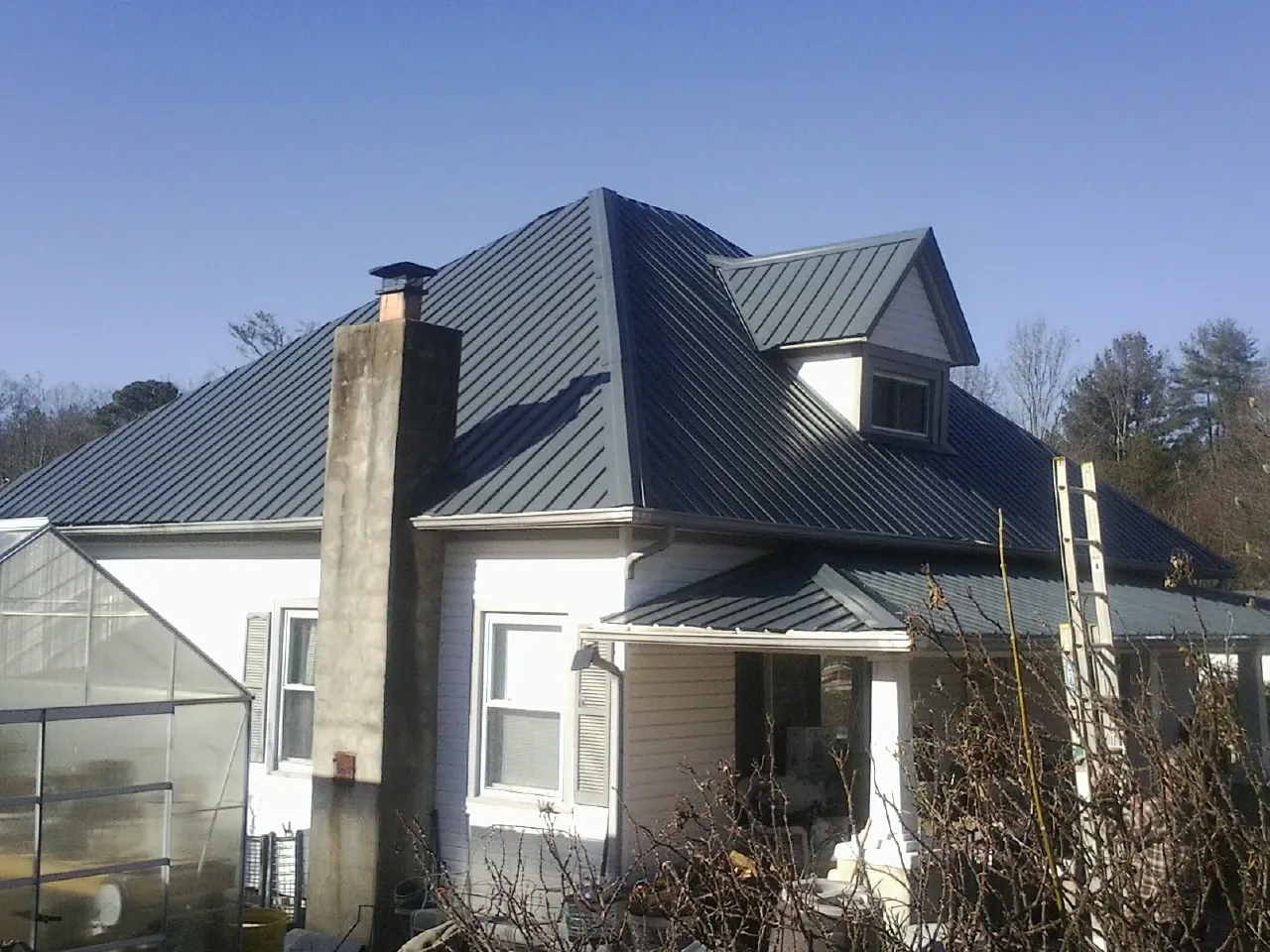 Dark blue standing seam metal roof on a white farmhouse with dormer — Slate & Tile Roof Repair by Roofing Brothers in Mullica Hill