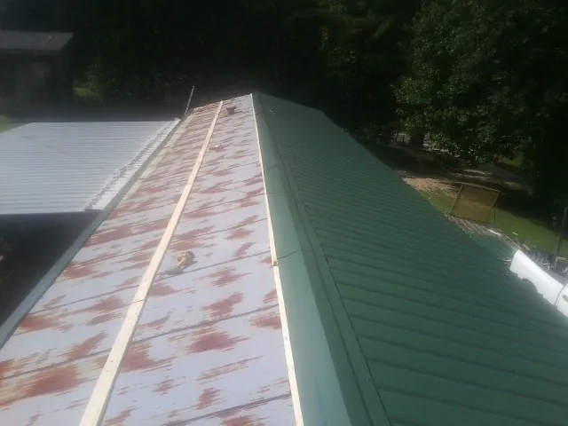 Old rusted panels beside newly installed green metal roofing — Wind Damage Roof Repair by Roofing Brothers in Mullica Hill