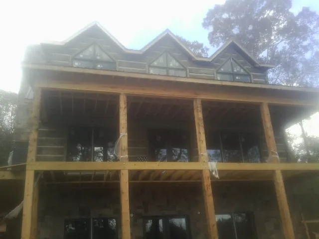 Dormers and porch framing on a large log home under construction — Roof Coating work by our crew in Mullica Hill