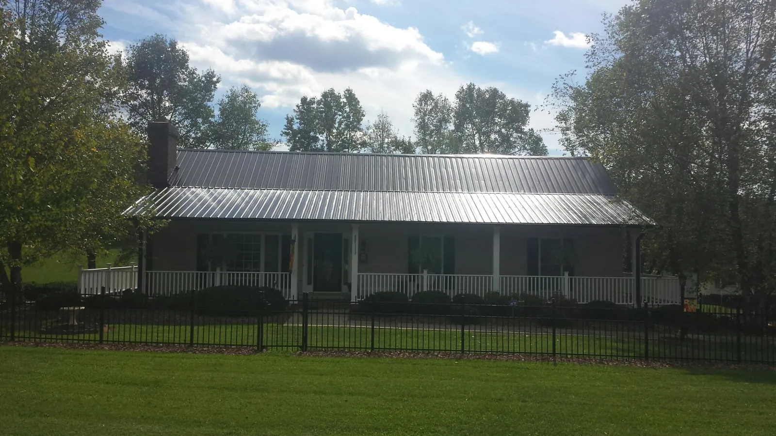 Gray metal roof on a brick ranch with a full width front porch — Gutter Guard Installation work by our crew in Mullica Hill