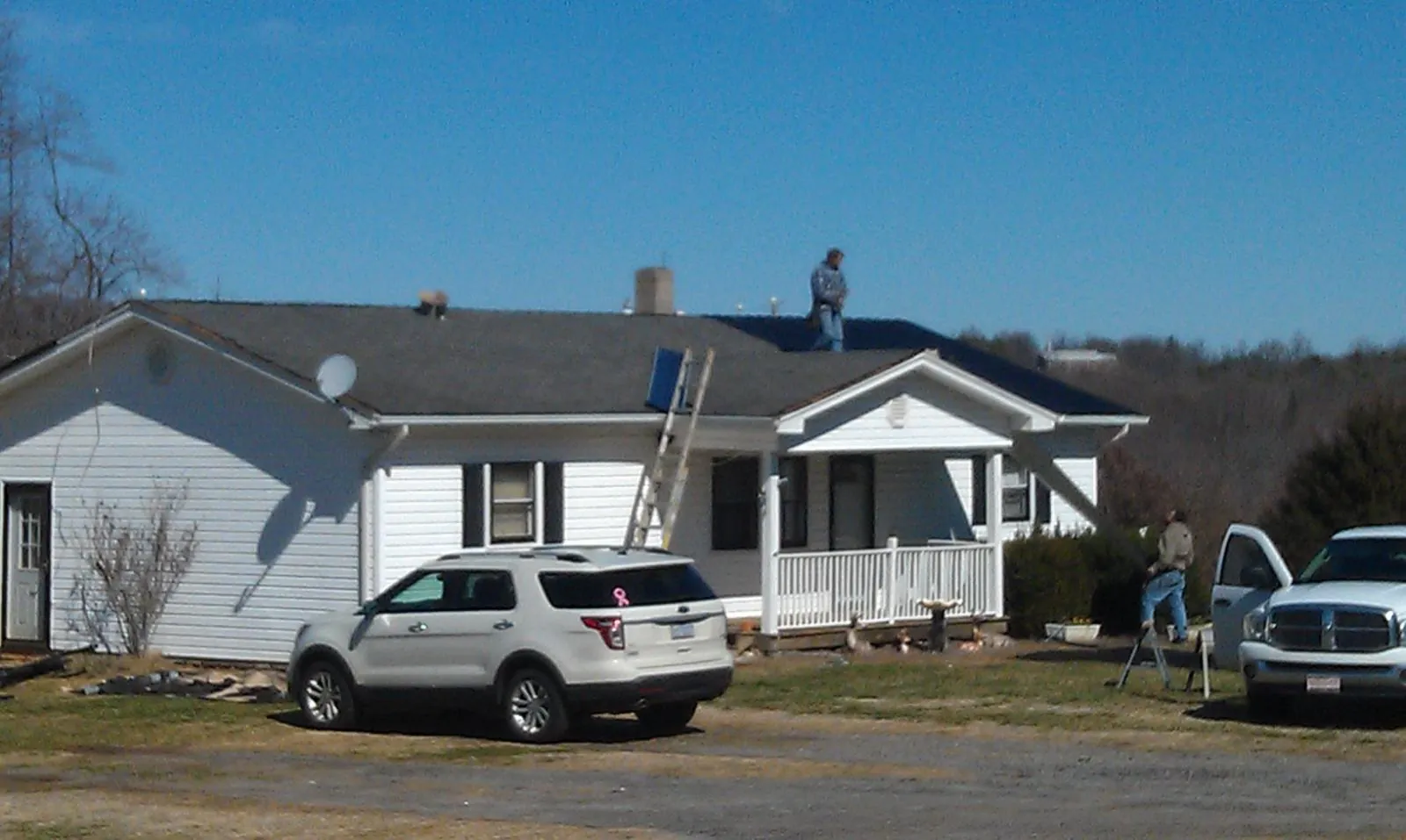 Roofers stripping shingles from a white ranch house roof in Mullica Hill