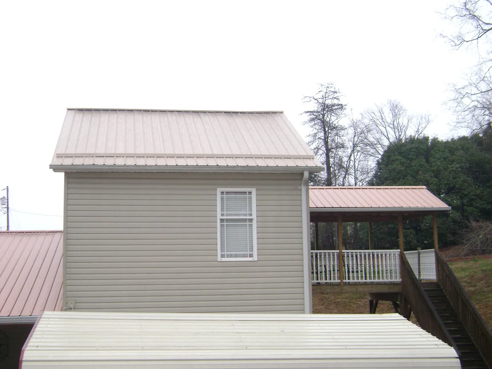 Tan metal roofs on a two story addition and attached porch, from a Roof Replacement job in Mullica Hill