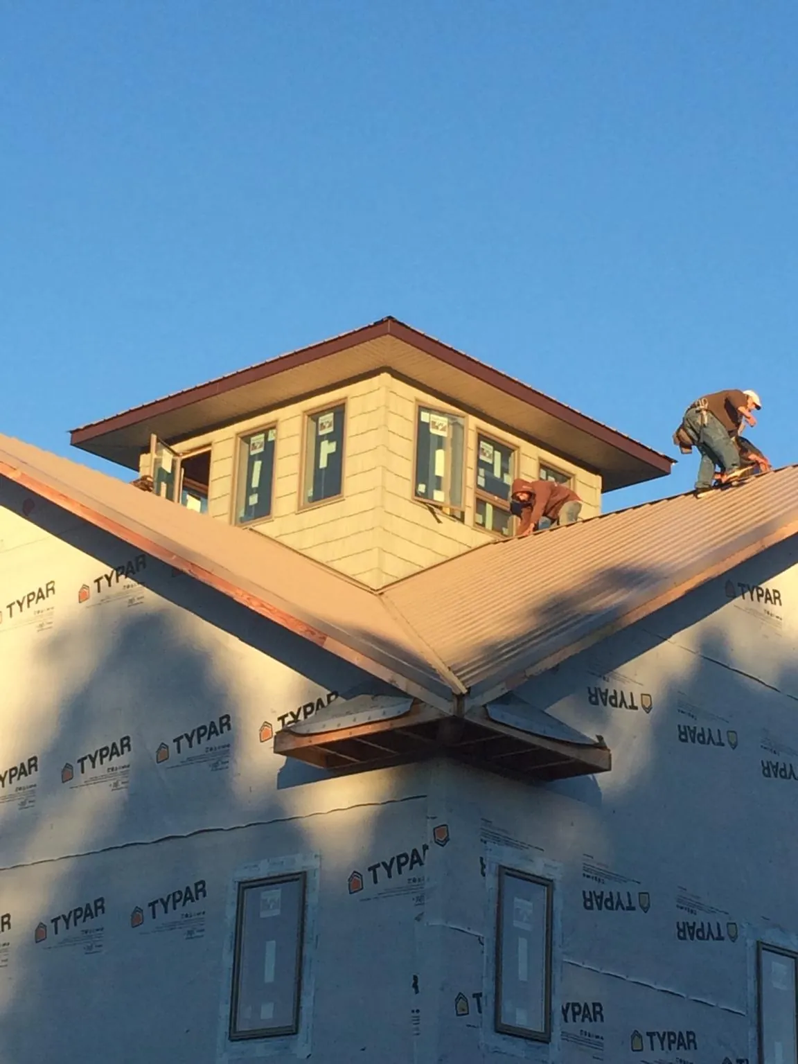 Roofers working around a rooftop cupola on a new metal roof at sunset — Roof Waterproofing in Mullica Hill by Roofing Brothers